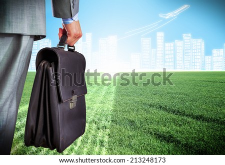 Rear view of businessman with briefcase and sketches at background
