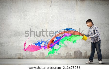 Young boy splashing colorful paint from bucket