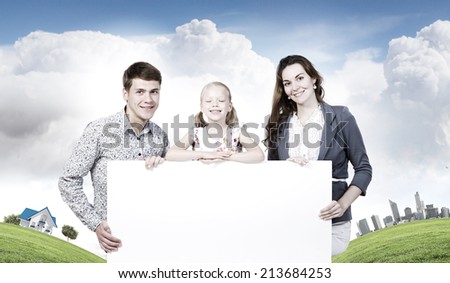 Happy family of three holding white blank banner. Place for text