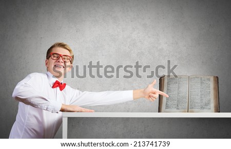 Young man in glasses pointing at opened book