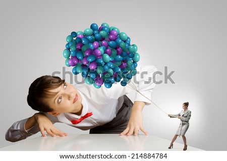 Businesswoman looking at businesswoman miniature pulling bunch of balloons