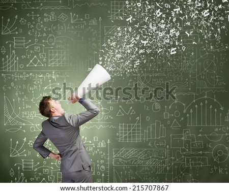 Young businessman speaking in trumpet with business sketches on wall
