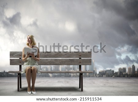Young pretty woman sitting on bench and reading book