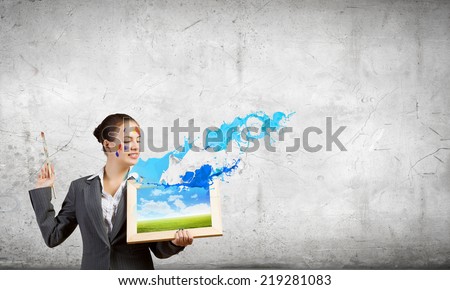 Young attractive woman in suit with paint brush in hand