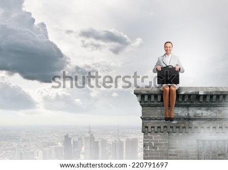 Young pretty businesswoman sitting on top of building high above city