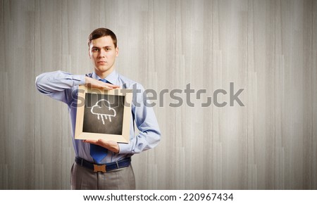 Young smiling businessman holding wooden frame with cloud sketch