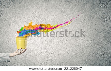 Close up of businesswoman holding bucket with paint splashes
