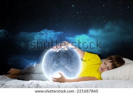 Cute boy lying in bed and dreaming about moon