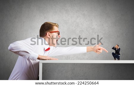 Angry businessman screaming at miniature of woman colleague