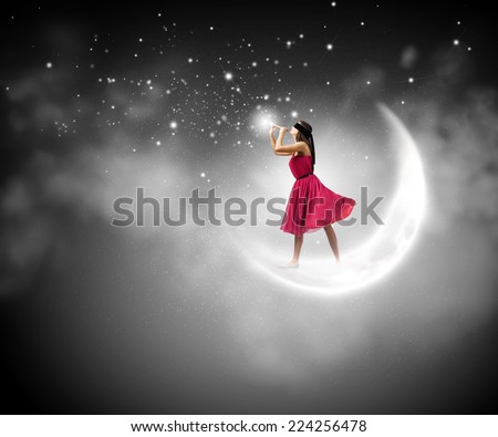 Young woman in red dress standing on moon and playing fife