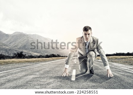 Young businessman standing in start pose ready to run