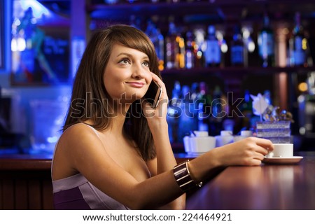 Young attractive lady at bar talking on phone