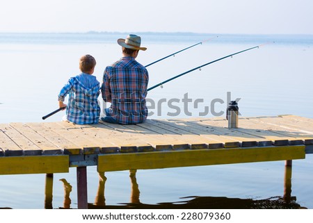 boy and his father fishing together from a pier