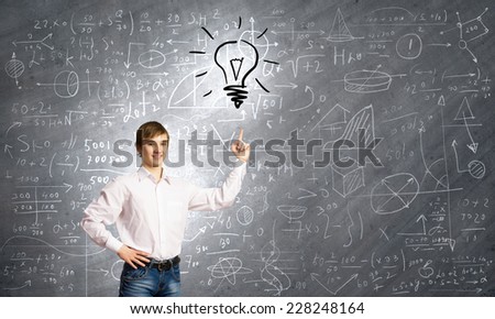 Smiling school boy pointing at light bulb with finger
