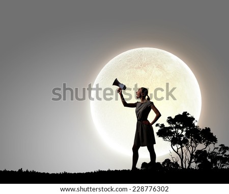 Young woman speaking in megaphone against full moon