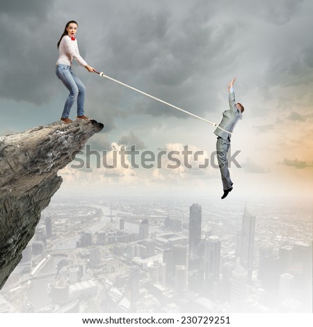 Woman holding on rope businessman trying to escape
