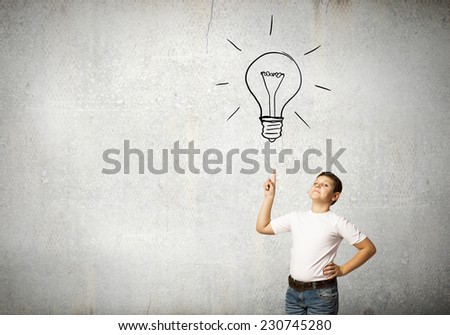 Smiling school boy pointing at light bulb with finger