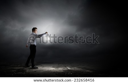 Young handsome businessman walking in darkness with lantern