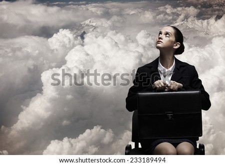 Upset businesswoman sitting on chair with suitcase in hands