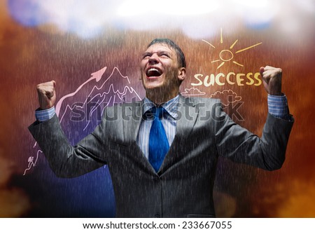 Young joyful businessman with hands up celebrating success