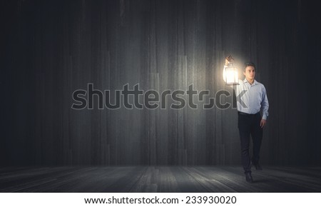 Young handsome businessman walking with lantern in darkness