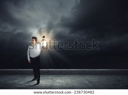 Young handsome businessman walking with lantern in darkness