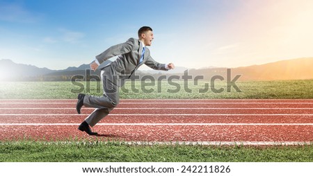 Young businessman in suit running on track
