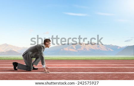 Side view of young businessman in start position on track