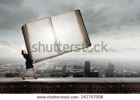 Young businesswoman in paper crown carrying huge book