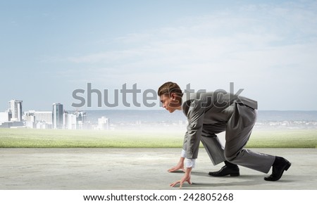 Side view of young businessman in start position ready to run