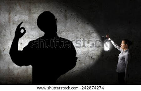 Young businesswoman walking in darkness with lantern in hand