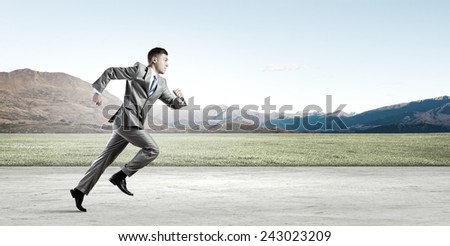 Young businessman in suit running on road