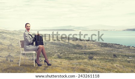 Young businesswoman sitting in chair against nature landscape