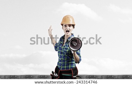 Young woman builder screaming emotionally in megaphone