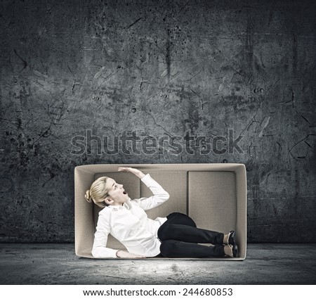 Young emotional woman trapped in carton box