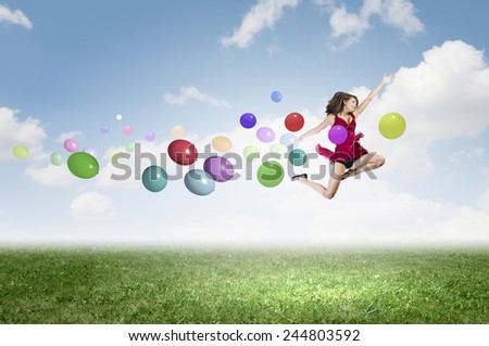 Young cheerful lady in red dress jumping high