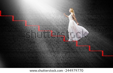 Young woman in white long dress stepping up the staircase