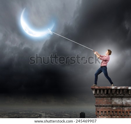 Young man in casual catching moon with rope