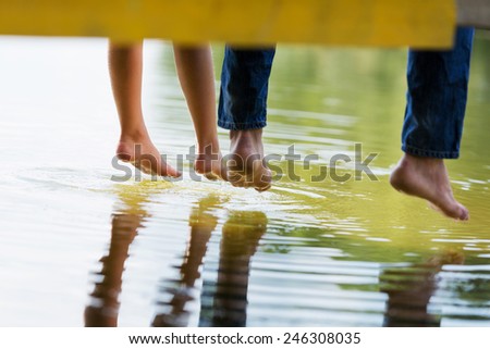 Close up of people\'s feet sitting on bridge