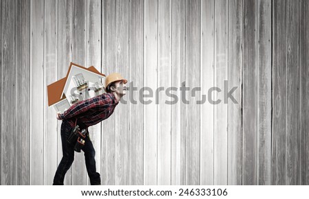 Young smiling craftsman carrying house model on back