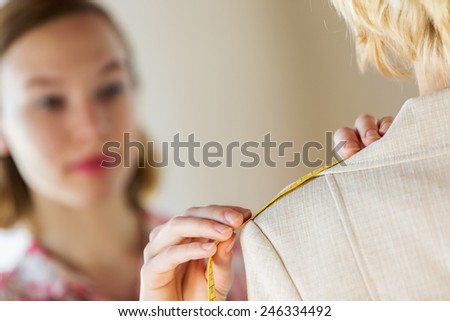 Pretty dressmaker at work making measures of client