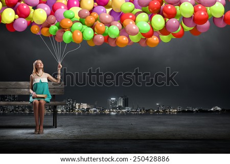 Young pretty girl with bunch of balloons sitting on bench