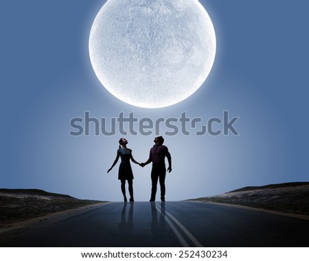 Silhouettes of young romantic couple standing under the moon light