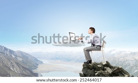 Young man sitting in chair and using laptop
