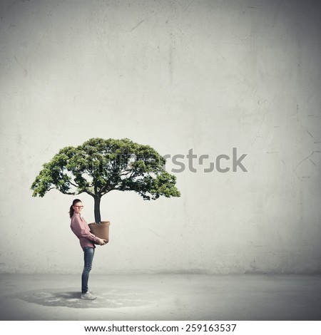 Young girl student carrying big green plant in pot