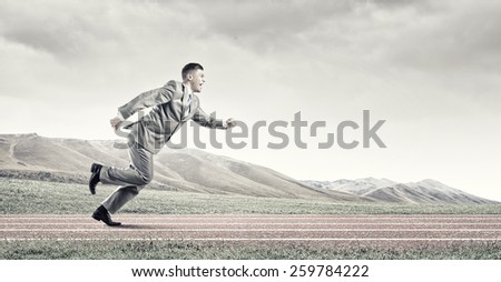 Young businessman in suit running on stadium track