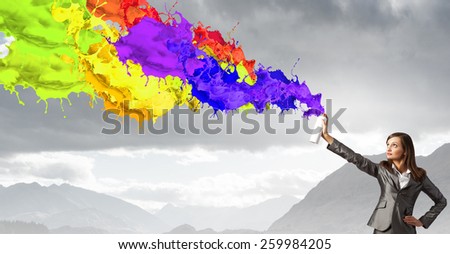 Businesswoman spraying colorful paint splashes from container