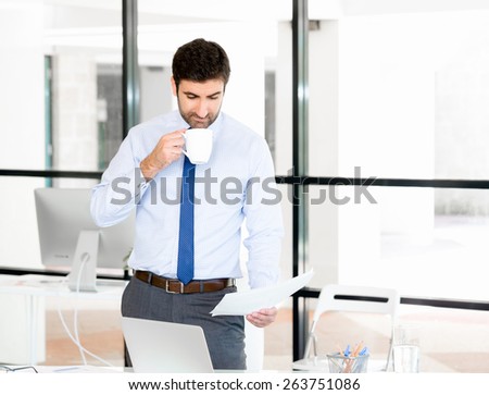 Young businessman in office with a mug and papers