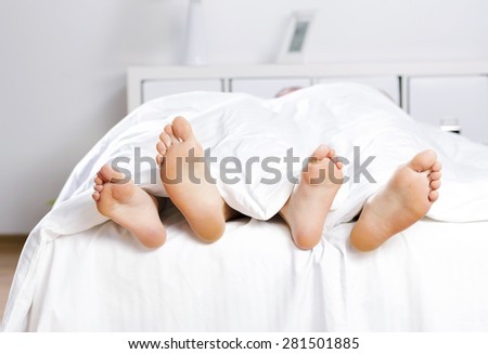 Close up of four feet in a bed