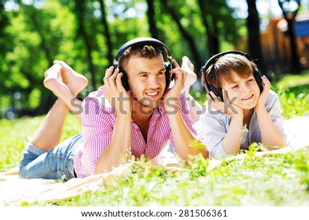 Father and kid in summer park enjoying music